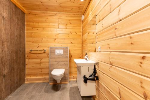 a bathroom with wooden walls and a toilet and a sink at Gladheimar Guesthouse in Blönduós