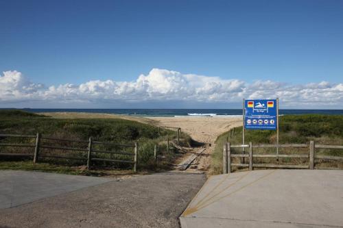 a sign on the side of a road next to a beach at Windang Tourist Park in Windang