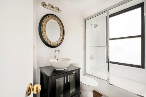 y baño con lavabo, aseo y espejo. en 139-3E west village 1BR best value, en Nueva York