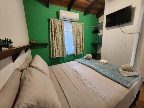 a bedroom with a green wall and a bed with towels at Villas Pura Vibra in Potrero
