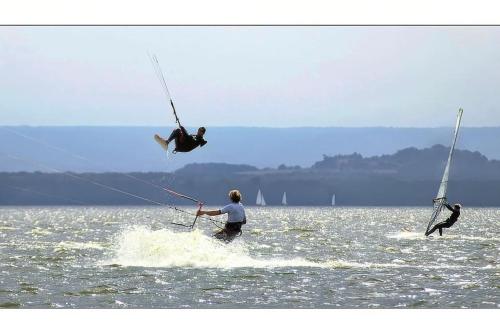 two people are windsurfing in a body of water at Janines Loft - Am Marktplatz Steinhude - 190 Meter zum Meer in Steinhude
