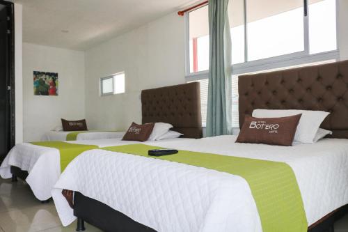 two beds with white and green sheets in a room at Hotel Casa Botero 303 in Bogotá