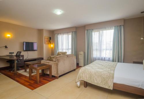 Habitación de hotel con cama, sofá y escritorio en Taarifa Suites by Dunhill Serviced Apartments en Nairobi