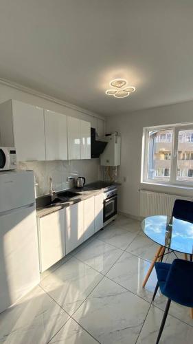 a kitchen with white cabinets and a table and a window at Bucharest luxury apartments Bragadiru in Bragadiru