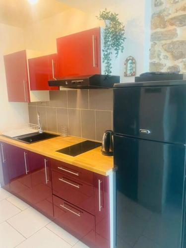 - une cuisine avec des placards rouges et un réfrigérateur noir dans l'établissement Appartement Neuf Cosy Centre Ville Quartier Haut, à Sète