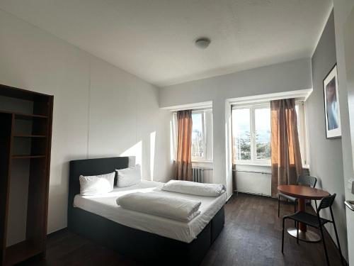a bedroom with a bed and a table and two windows at Ootel.com in Berlin