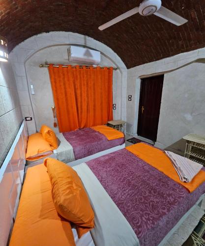 two beds in a room with an orange curtain at ABU Guest House in Aswan