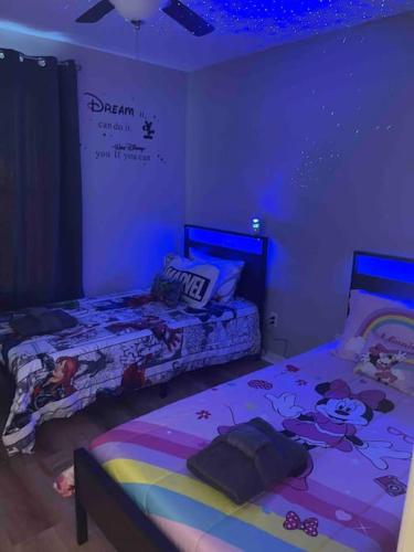 two beds in a room with purple lights at Vashay's Lovely vacation pad at Disney in Davenport
