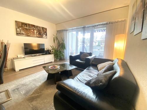 un soggiorno con divano in pelle e TV di Zentrale 4-Zimmer-Wohnung in Sirnach a Sirnach