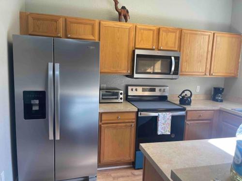 a kitchen with a stainless steel refrigerator and wooden cabinets at Vashay's Lovely vacation pad at Disney in Davenport