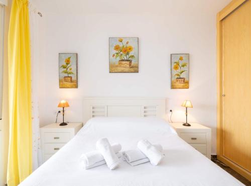 1 dormitorio con 1 cama blanca y 3 pinturas en la pared en Sunset Apartment Fuengirola, en Fuengirola