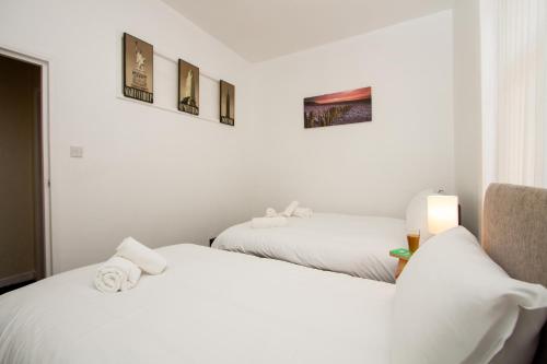 2 łóżka w pokoju z białymi ścianami w obiekcie Metropolitan Charm: Stylish 2BR House w Manchesterze