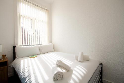 um quarto com uma cama branca e toalhas em Metropolitan Charm: Stylish 2BR House em Manchester