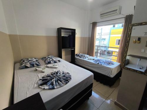 a room with two beds and a window at Hotel Mãe Rainha in Aparecida
