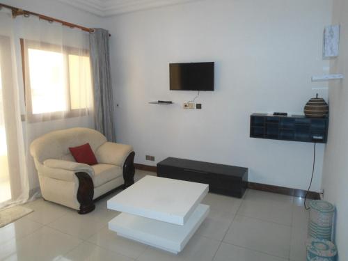 een woonkamer met een stoel en een tv aan de muur bij Daaru Jamm in Dakar