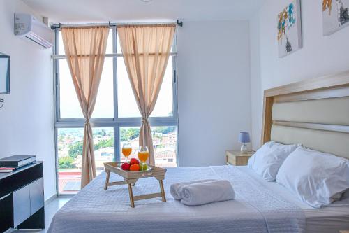 Volcano Views Apartment في سان سلفادور: غرفة نوم بسرير مع طاولة عليها فاكهة