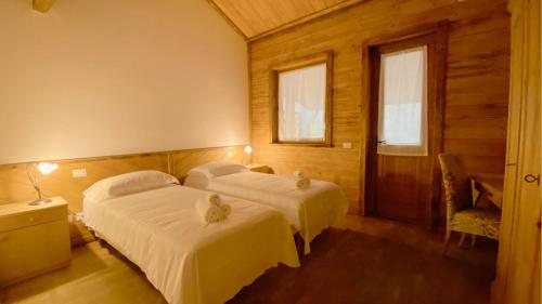 sypialnia z 2 łóżkami i krzesłem oraz 2 oknami w obiekcie Locanda Al Cacciatore w mieście Nervesa della Battaglia