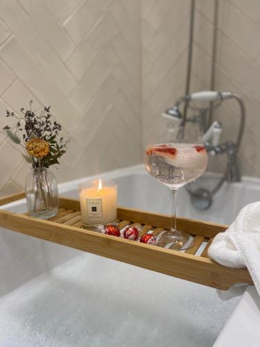 a bath tub with a candle and a wine glass at Bents Holiday Cottage, Views & Parking for two cars in Oxenhope