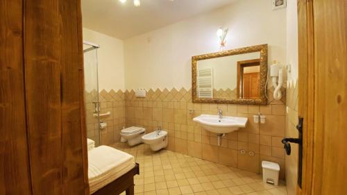 a bathroom with a sink and a toilet and a mirror at Locanda Al Cacciatore in Nervesa della Battaglia
