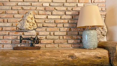 a lamp sitting on a table next to a brick wall at Locanda Al Cacciatore in Nervesa della Battaglia