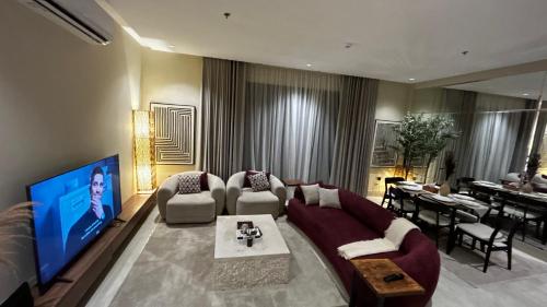 een woonkamer met een bank en een televisie bij M Residence - العبيكان هلز 3 in Riyad