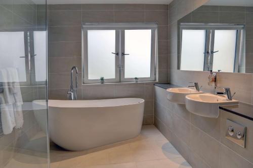 a bathroom with two sinks and a tub and two windows at Invercarse Hotel Dundee, BW Signature Collection in Dundee
