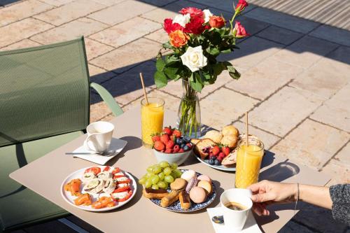 a table with plates of food and a vase of flowers at Best Western Hotel du Roy d'Aragon in Bonifacio