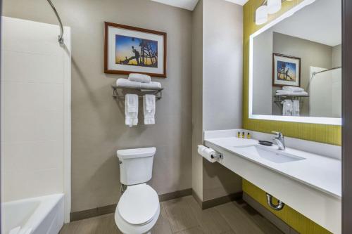a bathroom with a toilet and a sink and a mirror at Best Western Plus Taft Inn in Taft