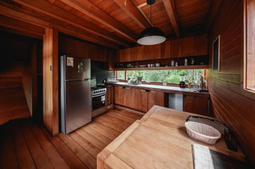 a kitchen with a stainless steel refrigerator and wooden cabinets at Lodge Parque Tepuhueico in Castro