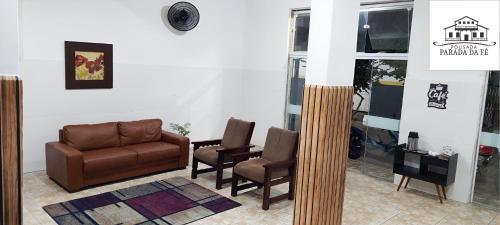a living room with a couch and two chairs at Pousada Parada Da Fé in Aparecida
