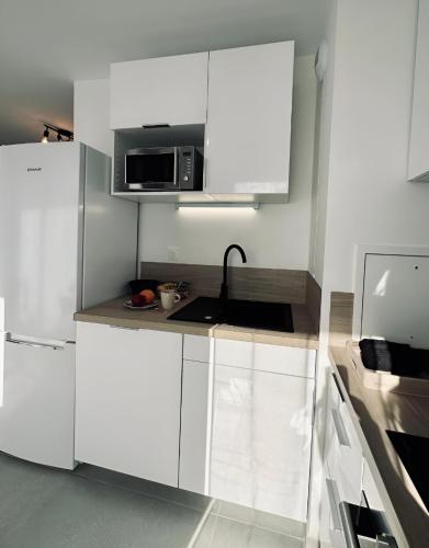a kitchen with white cabinets and a microwave at Disneyland-PARIS Sunshine - 6pers - Terrasse - vue sur Parc - 2Parkings in Chessy