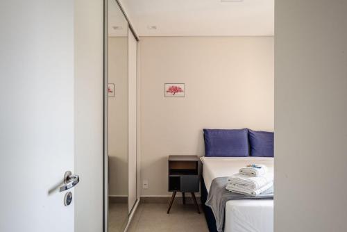 um quarto com uma cama com almofadas azuis e um espelho em Piscine Resort - Um Oasis no centro de SP | Canal do Anfitrião em São Paulo