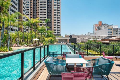 uma varanda com piscina, mesas e cadeiras em Piscine Resort - Um Oasis no centro de SP | Canal do Anfitrião em São Paulo