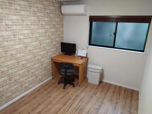 an office with a desk with a computer and a window at IIIホーム in Shijonawate