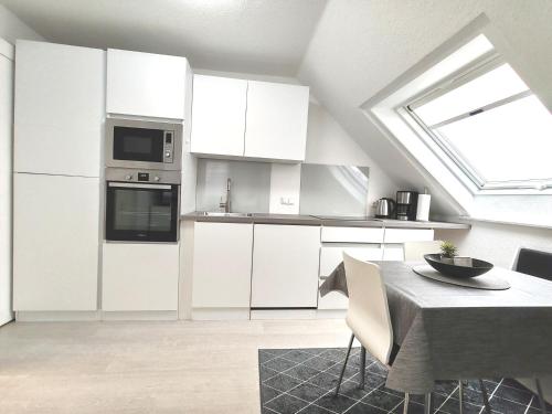 a kitchen with white cabinets and a table and a window at Top Wohnung in Mainz-Kostheim in Mainz-Kostheim