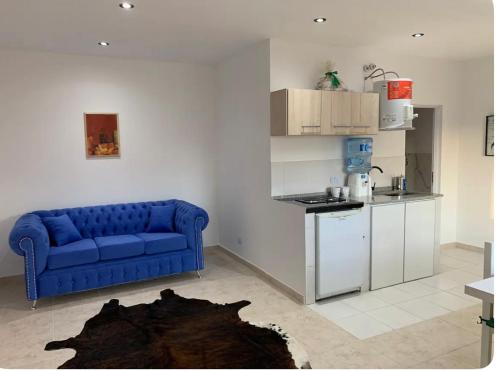 een woonkamer met een blauwe bank en een keuken bij Apartamento Entero a minutos del aeropuerto in Ezeiza