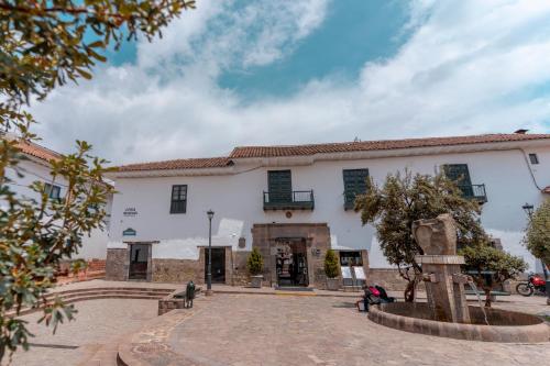 ein großes weißes Gebäude mit grünen Rollläden in der Unterkunft Casa Andina Premium Cusco in Cusco