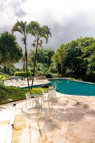 a pool with chairs and palm trees in front of it at Royal Palm Galapagos, Curio Collection Hotel by Hilton in Bellavista