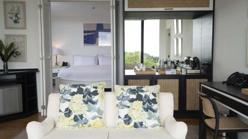 a bedroom with a bed and a white chair with pillows at Royal Palm Galapagos, Curio Collection Hotel by Hilton in Bellavista