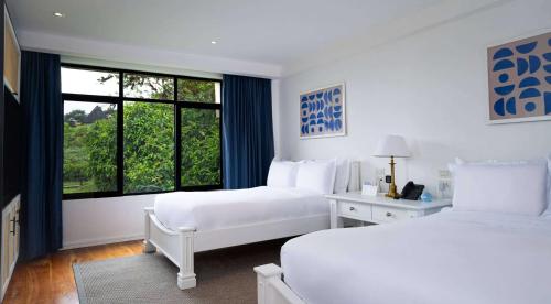 a white bedroom with two beds and a window at Royal Palm Galapagos, Curio Collection Hotel by Hilton in Bellavista