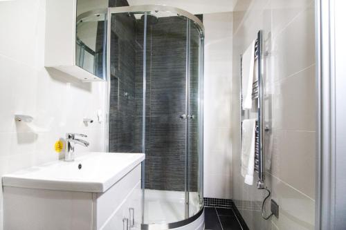 a white bathroom with a shower and a sink at Stylish modern 1 bedroom property in Greenwich! in London