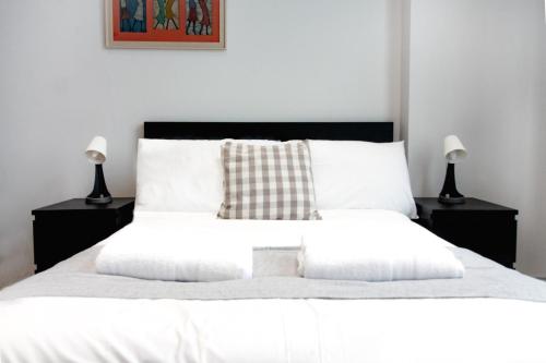 een slaapkamer met een wit bed en 2 nachtkastjes bij Stylish modern 1 bedroom property in Greenwich! in Londen