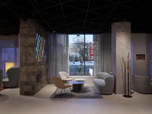 eine Lobby mit Stühlen, einem Tisch und einem großen Fenster in der Unterkunft Iceland Parliament Hotel, Curio Collection By Hilton in Reykjavík