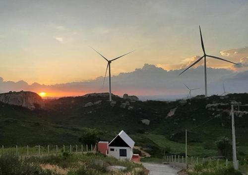 a group of wind turbines on a hill with the sunset at Chalé Monte das Gameleiras/RN in Monte das Gameleiras
