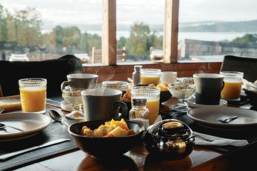 a wooden table topped with plates and bowls of food at Lodge Parque Tepuhueico in Castro