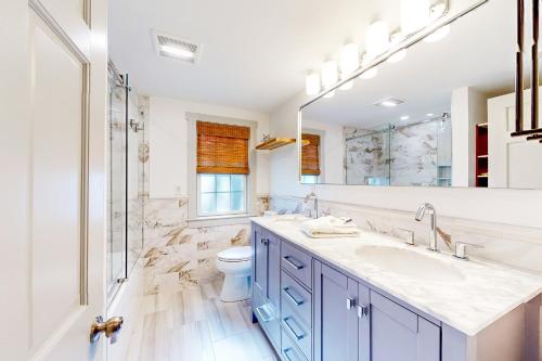 ein Badezimmer mit einem Waschbecken, einem WC und einem Spiegel in der Unterkunft Serene Sanctuary - A Family Oasis in Falmouth