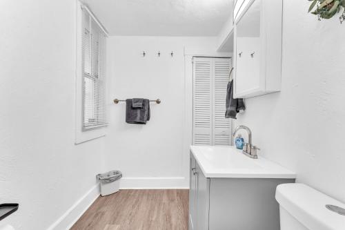 a white kitchen with a sink and a window at Cozy Med Haven: Little Italy in Cleveland