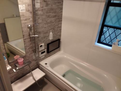 baño con bañera blanca y ventana en IIIホーム en Shijonawate
