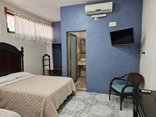 1 dormitorio con 1 cama y TV en una pared azul en Casa Xu´unan, en Valladolid