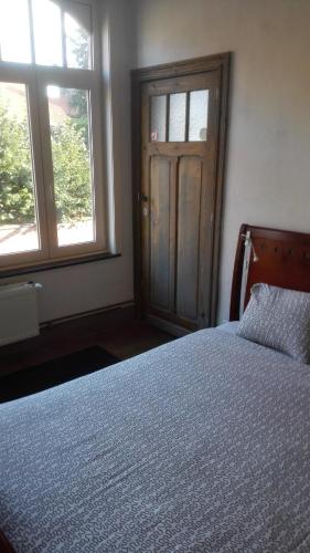 a bedroom with a bed and two windows and a door at Guesthouse Oude Houtmarkt in Ypres